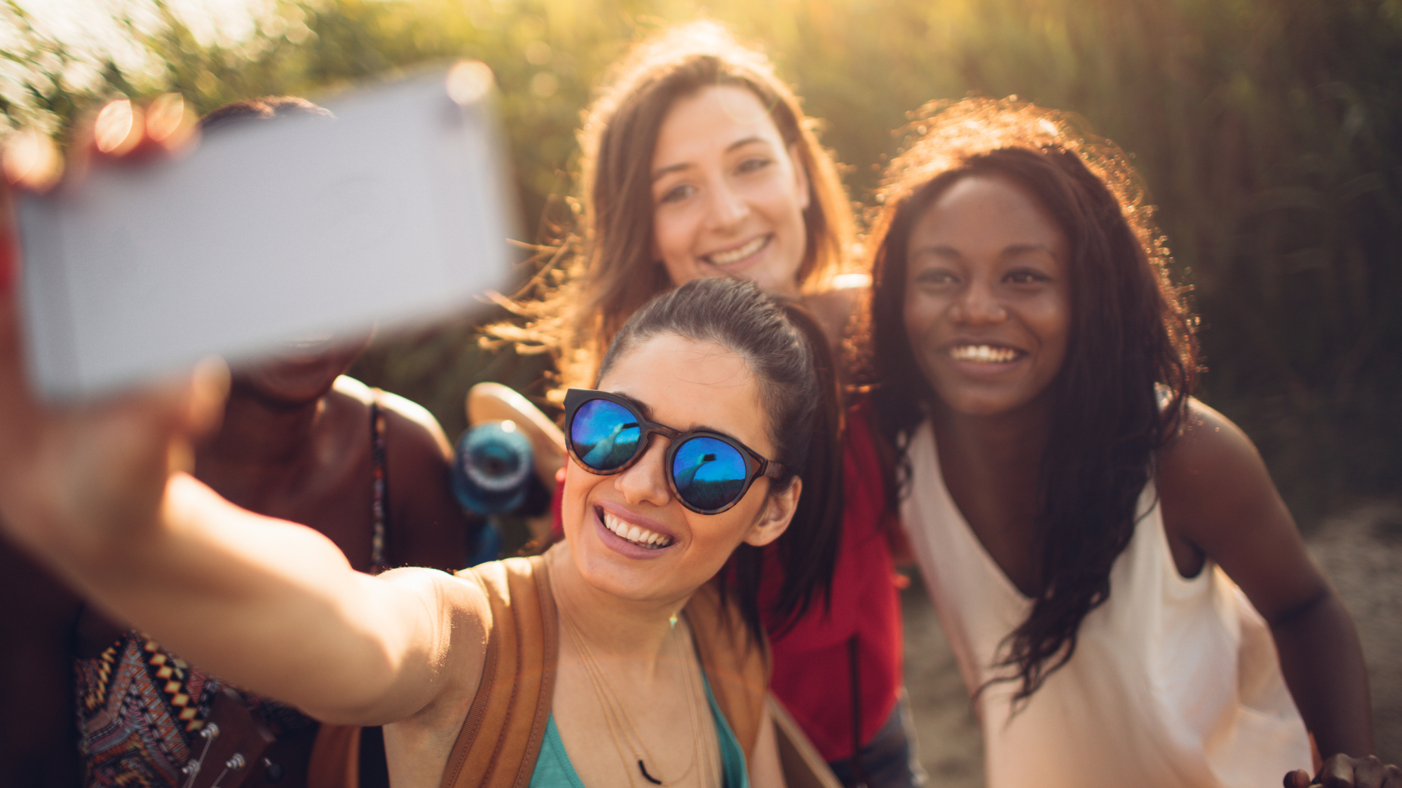 Friends taking a selfie outdoors in sunny weather, representing Spring Break group travel.