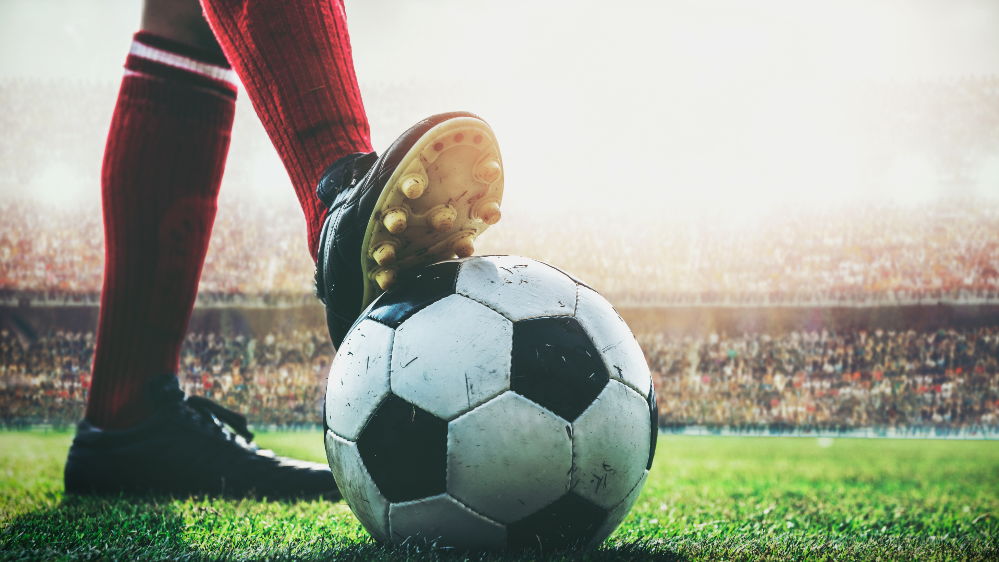 Soccer player’s foot resting on a ball in a packed stadium, symbolizing World Cup 2026 demand and peak travel season for short-term rentals.